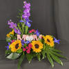 Colorful floral arrangement with sunflowers, purple blooms, and pink roses around a 