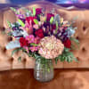 Bouquet of red roses, pink lilies, and hydrangea in a glass vase