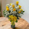 Yellow roses with white baby's breath in a glass vase tied with a yellow ribbon.