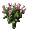Pink roses arranged in a tall glass vase with fern foliage
