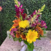 Colorful bouquet of yellow and orange flowers in a glass vase with a ribbon