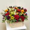 Mixed floral arrangement in a wooden box with red roses and green orchids
