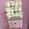 White roses arranged in a pink designer box with a gold chain handle