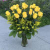 Yellow roses arranged in a clear glass vase with yellow filler flowers