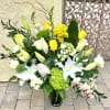 Large floral arrangement with white lilies, yellow roses, and green hydrangea in a vase