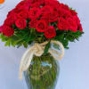 Red roses arranged in a clear glass vase with a rope bow