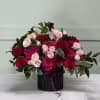 Bouquet of red and pink roses in a black vase with ribbon