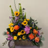 Mixed bouquet with sunflowers, roses, and purple blooms in a rustic basket