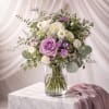 A soft bouquet of white and lavender roses with delicate daisy-like fillers