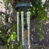 Silver wind chime hanging from a tree branch
