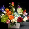 A lush, garden-style mixed bouquet arranged low in a white rectangular container-this