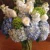 Vase arrangement of white roses, white stock, and green and blue hydrangeas