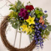 A bold circular wreath of mixed-color blooms mounted on a white easel-this