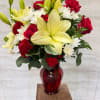Bouquet of red roses, white chrysanthemums, and yellow lilies in a red glass vase