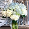 White and pale blue hydrangea bouquet in a clear glass vase