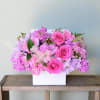 Pink and lavender flower arrangement in a white box