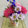 Mixed pink and purple flowers in a floral tin vase