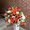 Bright, energetic orange roses, lilies, and gerbera daisies mingle with crisp white