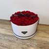 Round box filled with red roses and a black ribbon