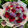 Bouquet of red roses and purple daisies wrapped in pale paper