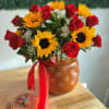 Red roses and bright sunflowers with white accents in a warm ceramic