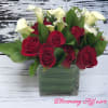 Red roses and white calla lilies in a square glass vase