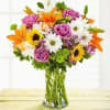 Mixed bouquet of orange lilies, purple roses, and white daisies in a glass vase