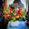 Tropical flower arrangement in a white vase with pink, orange, and yellow blooms