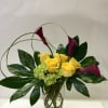 Yellow roses and purple calla lilies in a clear glass vase
