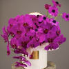 Bright magenta orchids arranged in a white hatbox vase