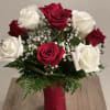 Red and white roses in a red vase with baby's breath