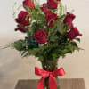 Red roses in a clear glass vase with a red ribbon