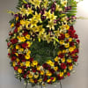 Large standing floral spray with yellow lilies, red roses, and purple orchids