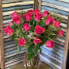 Hot pink roses arranged tightly in a pink glass vase with white