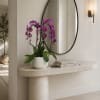 Purple orchids in a white pot on a stone console table