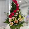 Tall arrangement of red, pink roses and lilies in a bright pink