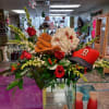 Baseball-themed floral arrangement with red roses and a red cap