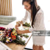 Woman arranging a colorful bouquet on a table