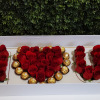 Red roses arranged with chocolates and a Baileys bottle in a gift box