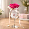 A single vivid pink rose arranged in a clear wine glass creates