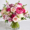 A lush, garden-style bouquet of roses and ranunculus in soft pinks, blush
