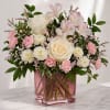 Creamy ivory roses and soft pink carnations create a gentle, romantic centerpiece