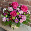 Hot pink roses rising above a nest of pink carnations and purple