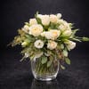 Cream-toned roses and white lisianthus mingle with airy greenery in a rounded