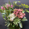 Pink tulips and roses arranged with white hydrangea in a glass vase
