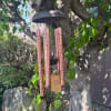 Copper wind chime hanging from a tree branch