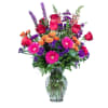 Mixed bouquet of roses, gerbera daisies, and purple flowers in a glass vase