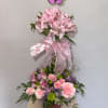 Pink floral arrangement with a butterfly topper and ribbon in a vase