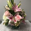 Soft pink lilies and pale pink roses sit above a dense cloud