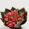 Bouquet of red tulips wrapped in black paper with gold trim